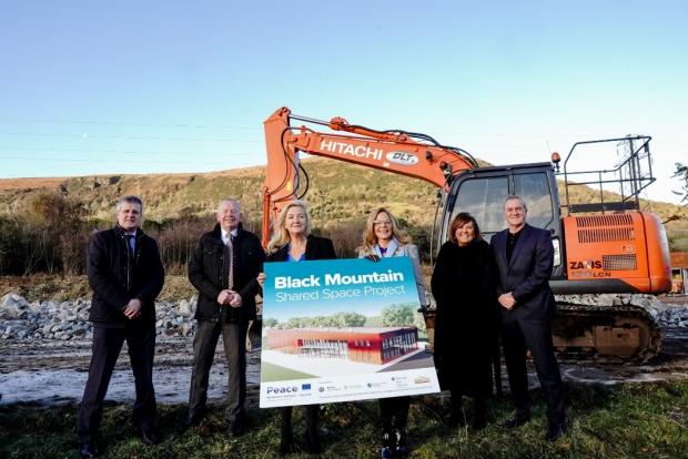 picture of six people standing in front of digger machinery with centre 2 people holding a large promotional graphic