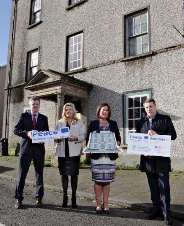 4 people holding image props outside old building