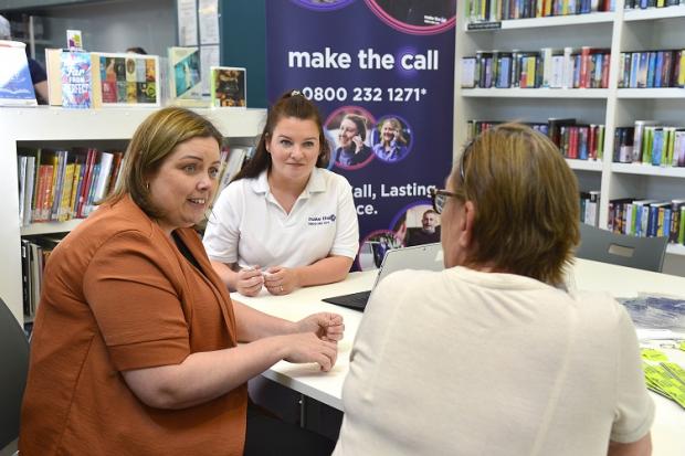 Communities Minister Deirdre Hargey is pictured chatting to Make the Call outreach officer, Amanda Milne and a library user who spoke to the Make the Call outreach team in Ormeau Library