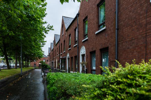 Image shows row of red brick terrace houses