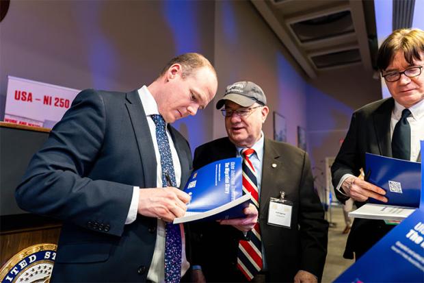 Minister Lyons signing a copy of “Ulster American Treasures: The Migration Story”