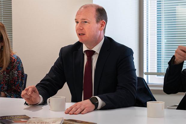 A mid-shot of Minister Lyons sitting at a table, across from America250 Executive Vice President, Jen Condon, talking