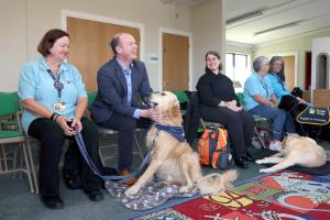 Communities Minister Gordon Lyons chats with Linda and her ambassador dog Parker at Carrickfergus Castle where Departmental officials have been working with Guide Dogs to make our monuments more accessible.