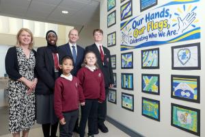 A man and a woman stand with a group of four children in school uniforms. Two children appear to be teenagers and the other two are younger children